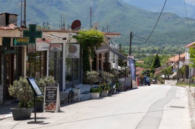Kastraki, Yunanistan - 30 Nisan 2025: Barışçıl cadde, sonsuz mavi gökyüzüne karşı Meteora 'nın yükselen kaya oluşumları tarafından çerçevelenmiş güneş ışığının tadını çıkarıyor