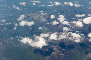 10.000 metre yükseklikten bulutların arasındaki karlı dağ zirvelerinin manzarası.