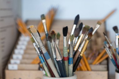 Suluboya, yağ ve akrilik fırçalar tek bir seramik bardakta toplanır, atölye ışığı altında yıkanır.