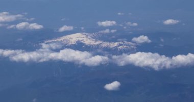 10.000 metre yükseklikten bulutların arasındaki karlı dağ zirvelerinin manzarası.