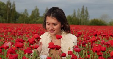 Genç çekici kadın gelinciklerin içinde oturuyor.