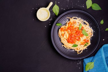 Siyah bir tabakta servis edilen karides ve peynirli lezzetli spagetti. İtalyan tarifi, domates sosu, sebze ve baharatlar.