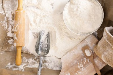Flour in a bowl and wheat grains with wheat ears on the table, paper background In a rustic kitchen, top view