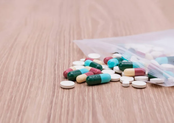 Colorful pills with capsules and pills in zip-lock plastic bags. Placed on the dispensing table, wooden background