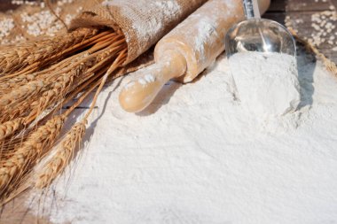 Buğday, arpa, pişirme, ekmek ve kurabiyelerden oluşan un ve kulaklar kırsal bir mutfaktaki ahşap masa zemininde düzenlendi. Üst görünüm.