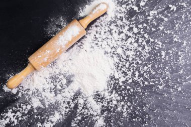 Heaps of wheat flour with ears of wheat on the table, black background - top view
