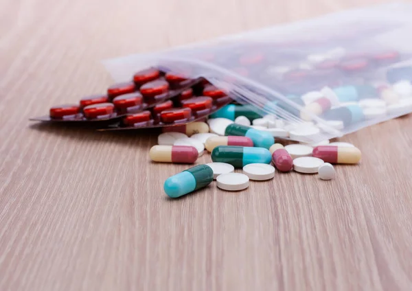 Colorful pills with capsules and pills in zip-lock plastic bags. Placed on the dispensing table, wooden background