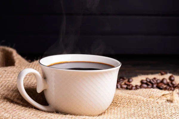新煮的咖啡 咖啡杯或杯子放在用烤咖啡豆做的黑色木制桌子上 黑背景的浓缩咖啡卡布奇诺咖啡店 图库照片