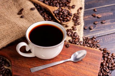 Taze demlenmiş kahve. Kahve fincanı ya da kupa kavrulmuş kahve çekirdekleri ile birlikte siyah ahşap bir masaya dizilmiş. Espresso mocha cappuccino barista koyu arka planda - üst görünüm