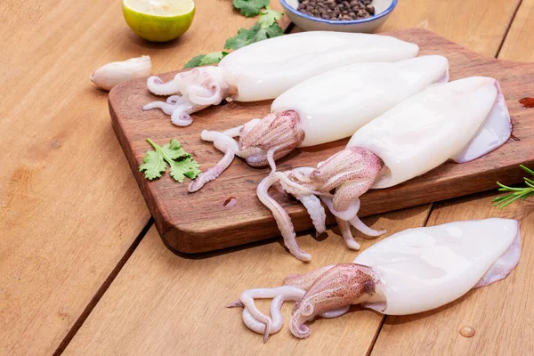 Ahşap arka planda ahşap bir deniz ürünleri menüsünde taze mürekkep balığı ya da çiğ mürekkep balığı. Üst görünüm.