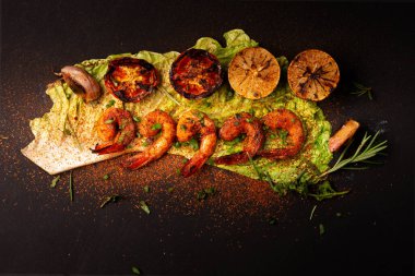 Koyu siyah arka planda ızgara karides ya da limon ve sarımsaklı barbekü. Deniz ürünleri. Üst görünüm.