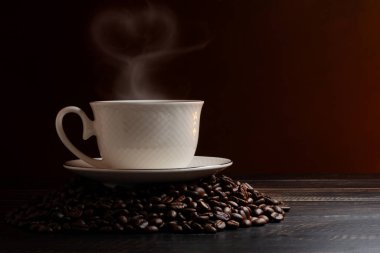Siyah kahve ya da kapuçino espresso bardağında sıcak çay, kahve çekirdekli kahvaltı, ahşap bir masada koyu bir arka planda izole edilmiş, üst manzara.