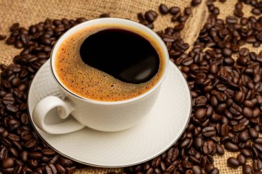 Siyah kahve ya da kapuçino espresso bardağında sıcak çay, kahve çekirdekli kahvaltı, ahşap bir masada koyu bir arka planda izole edilmiş, üst manzara.