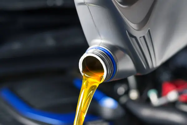 Pour car lubricant from a gray bottle on the background of the engine. Oil change service, auto repair shop Technology and transportation industry