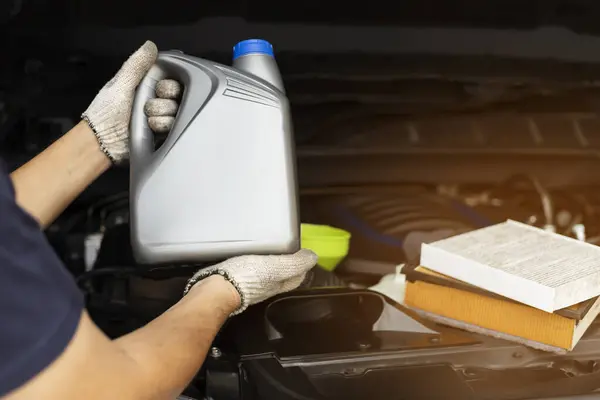 Car lubricant gallon or from gray bottle on engine background Oil change service, auto repair shop Technology and transportation industry