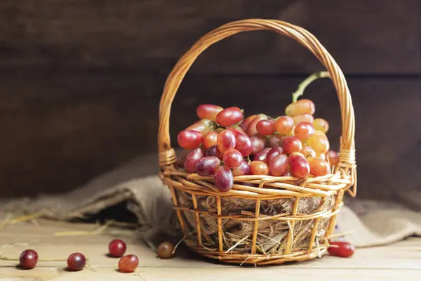 Red grapes, naturally sweet fruit, are placed on a wooden table and arranged in a wooden basket. on the old wooden background