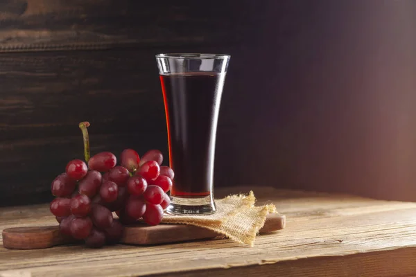 Red grape juice in a glass. Placed on a wooden table. Delicious natural fruit juice drink.