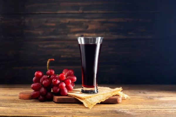 red grape juice in a glass placed on a wooden table or red wine, a delicious natural fruit juice drink