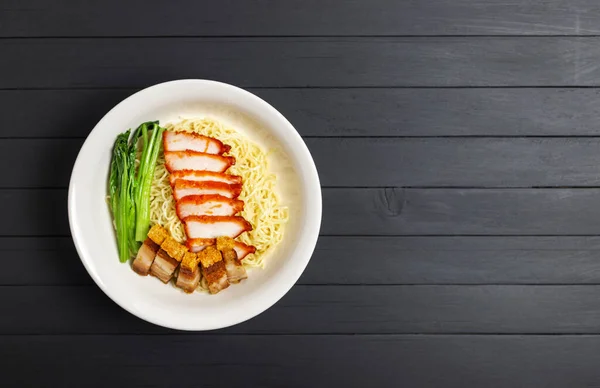 Pork noodles with pork, barbecue eggs, crispy pork, dumplings, green vegetables, healthy food, Thai, Chinese, Hong Kong, arranged on the wooden table, top view. with Copy space for text