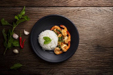 Tahta masaya yerleştirilmiş baharatlı Tayland yemeği ve fesleğenli karides. Üst görünüm.