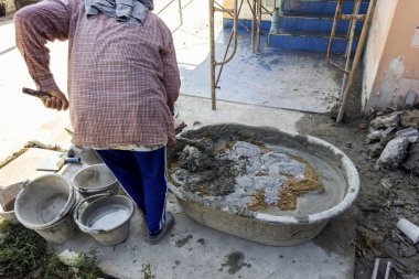 İnşaat, bina ve endüstri işlerinde plastik bir konteynırda beton karıştıran işçiler.