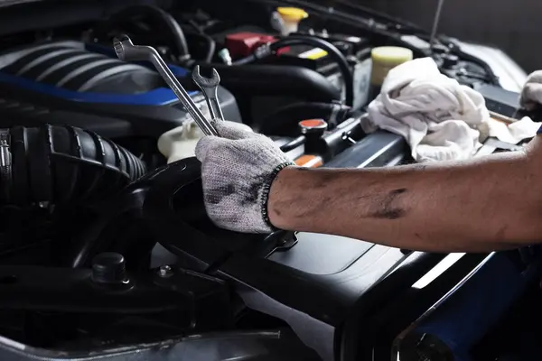 Car maintenance, vehicles, and automation technology, services Technician in hand uses wrench to repair broken car engine parts. and support car insurance services