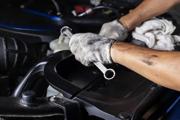 Car maintenance, vehicles, and automation technology, services Technician in hand uses wrench to repair broken car engine parts. and support car insurance services