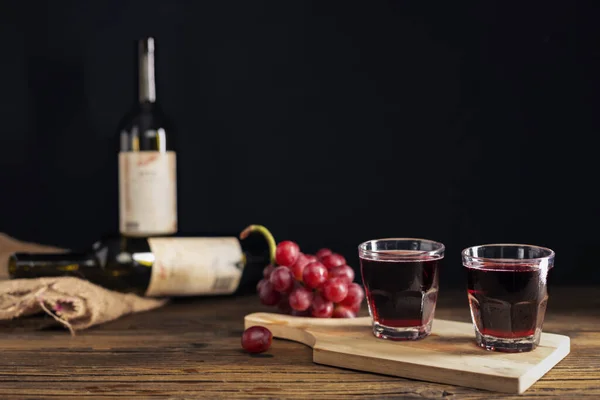 Red grape juice in a glass placed on a wooden table or red wine, a delicious natural healthy juice drink. With a bunch of fresh red grapes from the garden