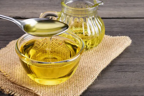 Kaşık kepçesi eski ahşap bir masaya konan bir fincanda sebze yağı..