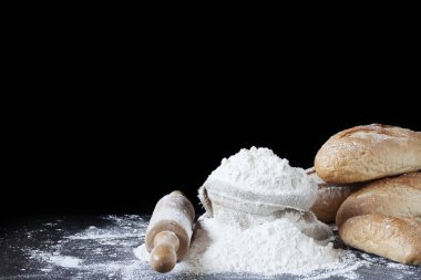 Buğday unlu torbalar rulo ekmekli ve masaya yayılmış beyaz toz siyah arka planda