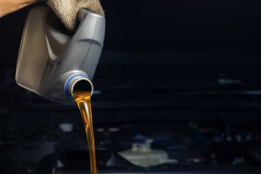 Kayganlaştırıcı şişeden motor yağı dök. Motor arka planı, yağ değişimi, motor hizmet sektörü