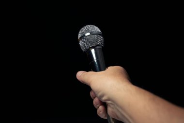 Modern şarkı sahnesinde mikrofon tutan gümüş renkli erkek mikrofon Siyah arka plan ve eller