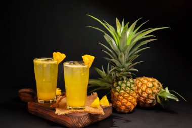 Bahçeden taze ananas ile ananas suyu sağlıklı yaz yemekleri, kokteyller, doğal içecekler yeşil yapraklar. Siyah arkaplanda izole.