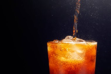 Bardakta buzla köpüklü suyu yakından çek. Siyah arkaplana yerleştirilmiş