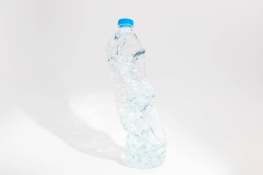 Geri dönüştürülmüş atık, ezilmiş şeffaf plastik su şişeleri beyaz arka planda.