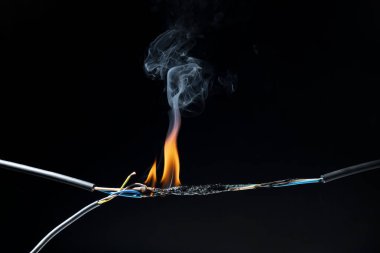 Elektrik şoklarından kaynaklanan alevler kısa devre kablolar kıvılcımlara, patlamalara, aşırı güç kullanımına, hasarlı ve standart olmayan ekipmanlara neden olur. koyu siyah bir arkaplanda