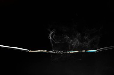 Kısa devre kablosundan çıkan duman kıvılcımlara, patlamalara ve aşırı elektrik tüketimine neden olabilir. Siyah arka planda hasarlı ekipman ve standart altı ekipman