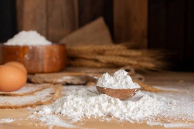 Arpa kulaklı ahşap kaşıkta beyaz buğday unu pirinç taneleri ve yumurtalar. Koyu ahşap arka planda doğal tarım yiyeceği.