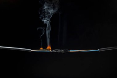Elektrik şoklarından kaynaklanan alevler kısa devre kablolar kıvılcımlara, patlamalara, aşırı güç kullanımına, hasarlı ve standart olmayan ekipmanlara neden olur. koyu siyah bir arkaplanda