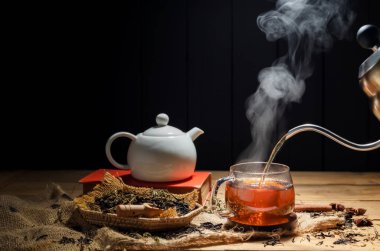 Sıcak çayı fincanlara dök, bitki çayı bardakları kırsal ahşap bir masada düzenlenir..