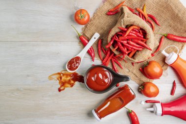 Ketçap, acı biber sosu, plastik sos şişeleri ve cam şişeler mutfaktaki ahşap masa, üst manzara.