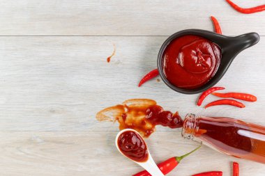 Ketçap, acı biber sosu, plastik sos şişeleri ve cam şişeler mutfaktaki ahşap masa, üst manzara.