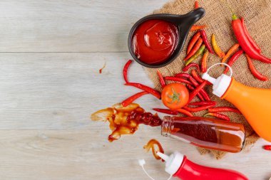 Ketçap, acı biber sosu, plastik sos şişeleri ve cam şişeler mutfaktaki ahşap masa, üst manzara.