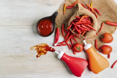 Ketçap, acı biber sosu, plastik sos şişeleri ve cam şişeler mutfaktaki ahşap masa, üst manzara.