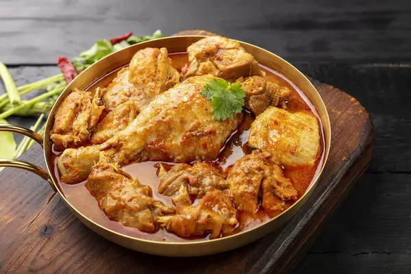 Körili tavuk Asya yemeği masalası. Geleneksel baharatlı sağlıklı yemek pişirme. Siyah ahşap masa arkaplanına yerleştirilmiş.