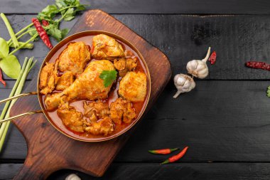 Körili tavuk Asya yemeği masalası. Geleneksel baharatlı sağlıklı yemek pişirme. Siyah ahşap masa arkaplanına yerleştirilmiş.