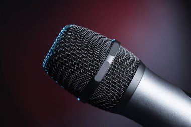 Stüdyoda mikrofona yakın çekim yapmak veya sahnedeki konser performansı, siyah arkaplan üzerine.