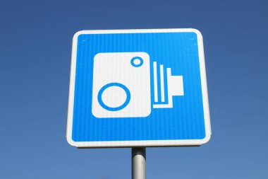 Açık mavi gökyüzüne karşı otomatik trafik güvenlik kamerası sembolü olan bir Finlandiya yol tabelasının alçak açılı görüntüsü.