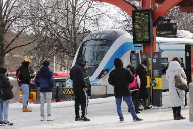 Sodertalje, İsveç - 11 Mart 2023: Sodertalje Centrum banliyö tren istasyonunda kar yağışı bekleyen insanlar.