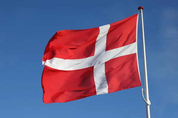 丹麦国旗在清澈的蓝天下迎风飘扬 免版税图库图片
